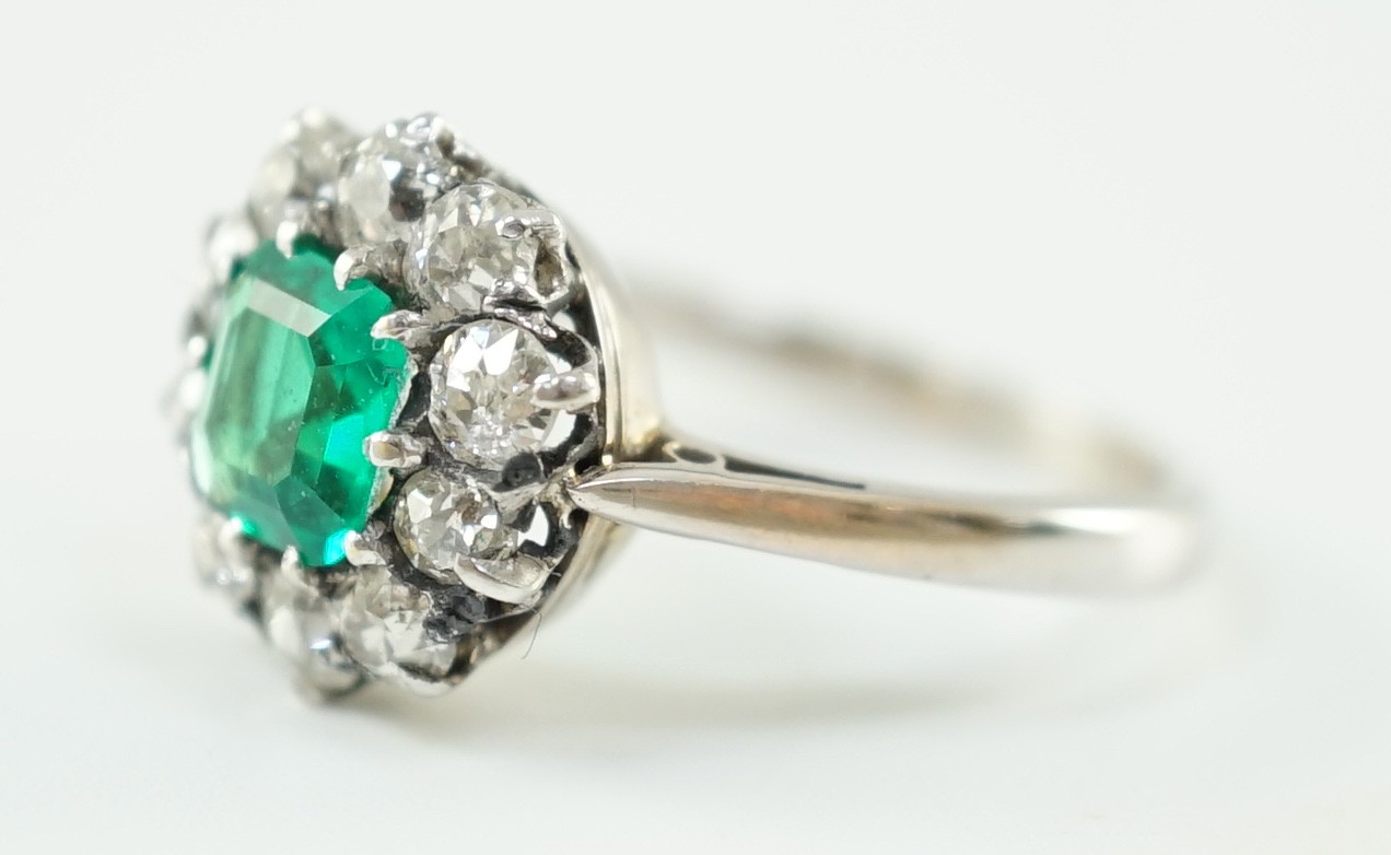 An early to mid 20th century, platinum, octagonal cut emerald and round cut diamond set circular cluster ring